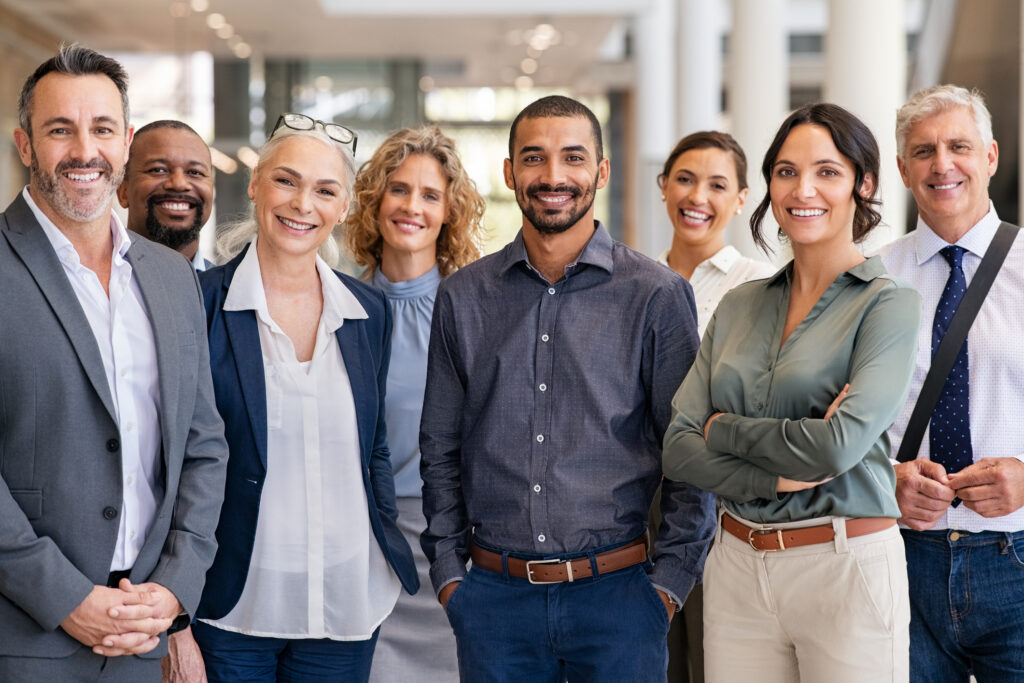 Group of business people at modern office looking at camera. Happy businessmen and satisfied businesswomen standing as a team.