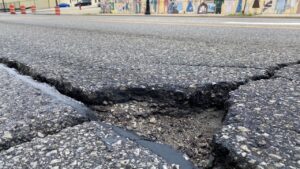 Pothole Outside of Sam's Club in Greensboro: A deep pothole near the entrance of Sam’s Club in Greensboro, visibly damaging to vehicles and symbolizing the widespread need for road repairs across the city.